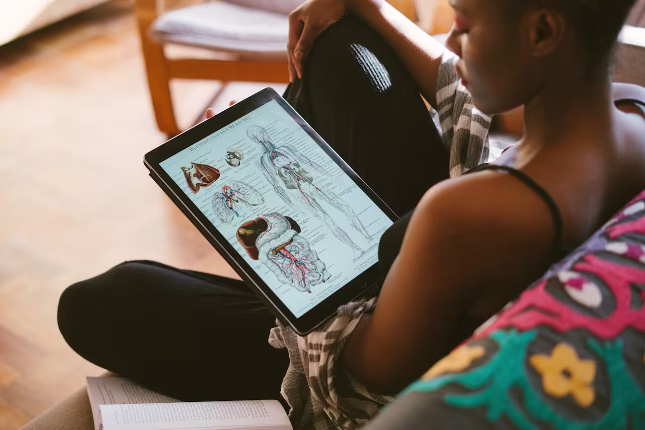 Woman studying anatomy diagrams at home on her tablet